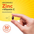 A hand holds a Zinc + Vitamin C softgel, 5/8 inch in size, with a bottle labeled '50 Quick Release Softgels' in the background.