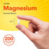 Vegan Ultra Magnesium caplet, 3/4'' long, shown held between fingers for size reference.